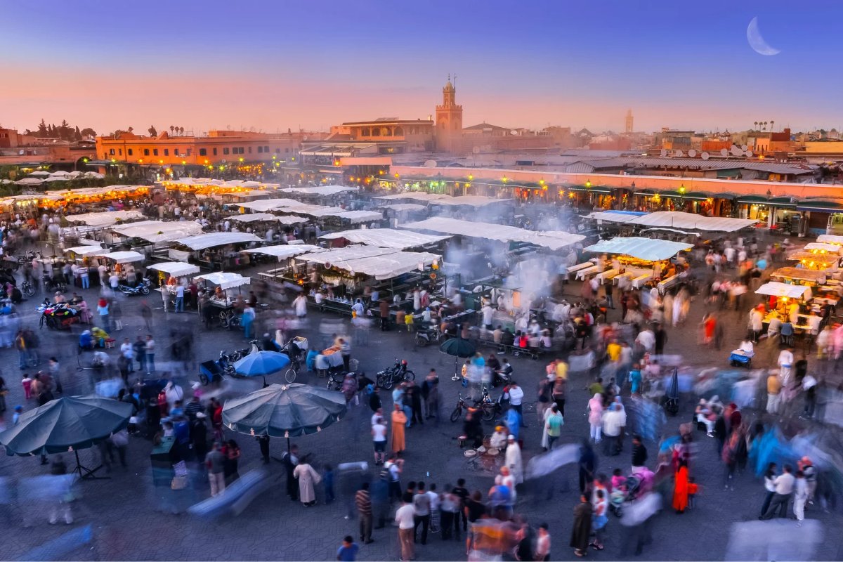 Jemaa el-Fnaa at dusk, Marrakech — stalls, smoke and the minaret under a crescent moon
